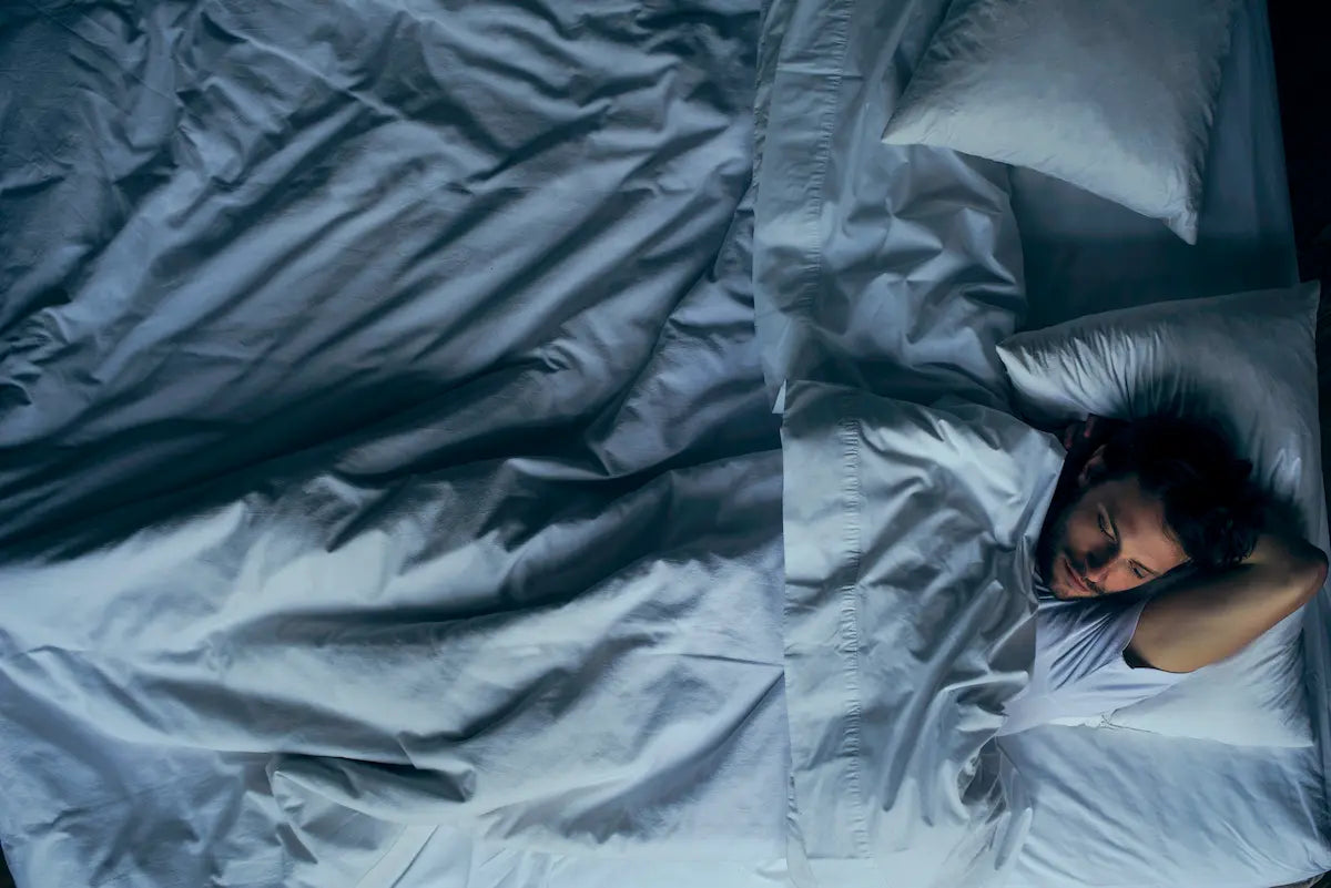 Homme allongé, les yeux ouverts, montrant des difficultés à trouver le sommeil.
