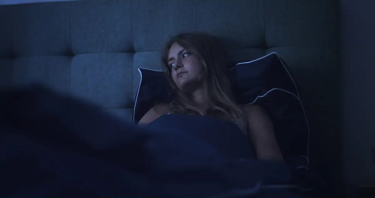Femme éveillée dans le noir, souffrant potentiellement de troubles du sommeil.