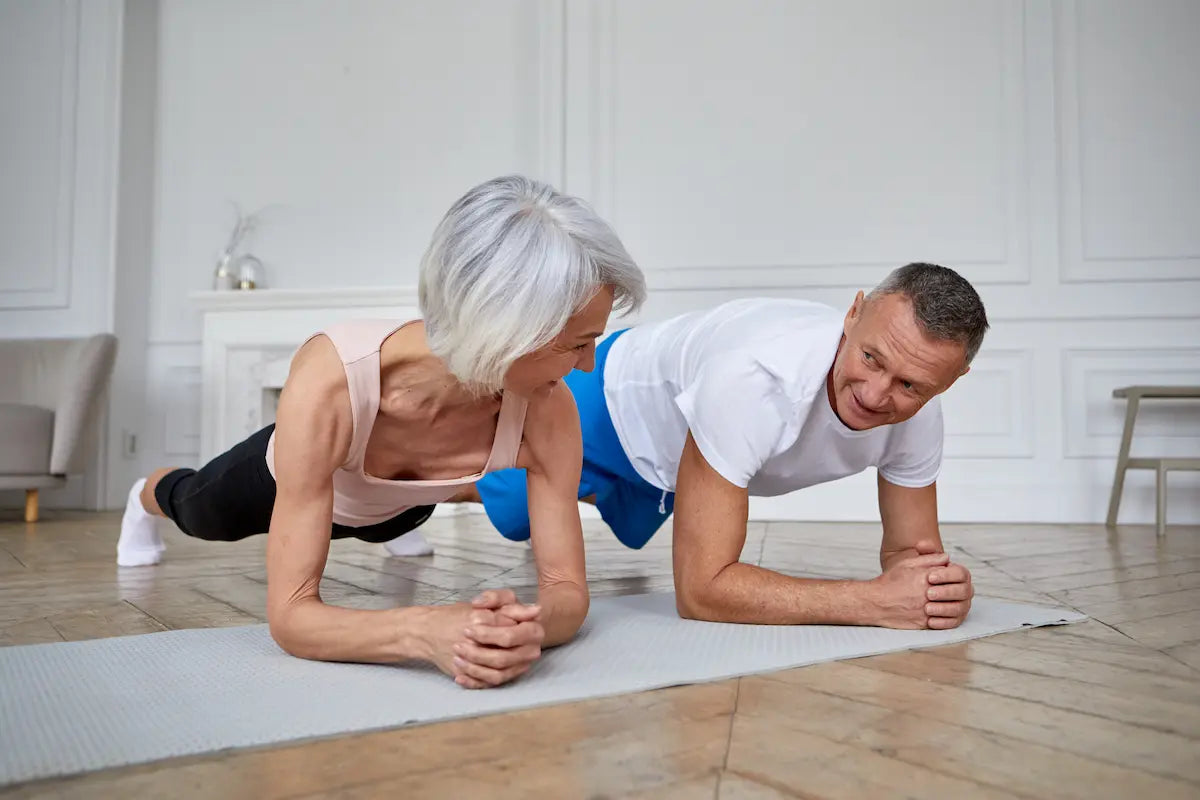 Couple senior en pleine séance de gainage, exercice ciblé pour renforcer la sangle abdominale et favoriser la perte de graisse.