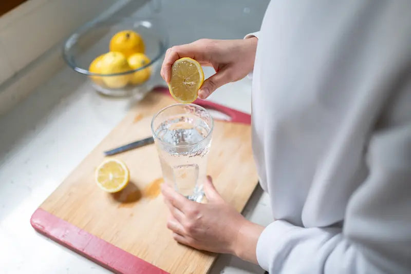 Une personne qui met du jus de citron dans de l'eau