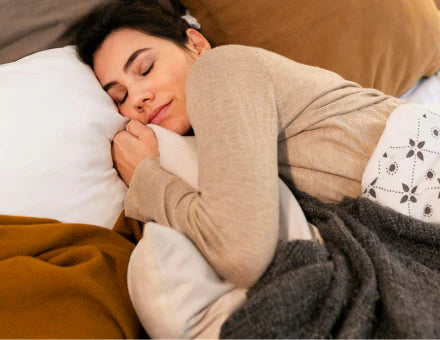 Femme détendue dans un lit, sommeil, mélatonine, bien dormir naturellement.
