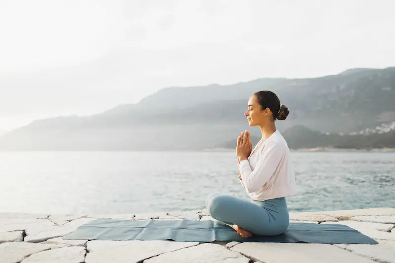 Femme qui médite au bord de l'eau pour calmer son mental
