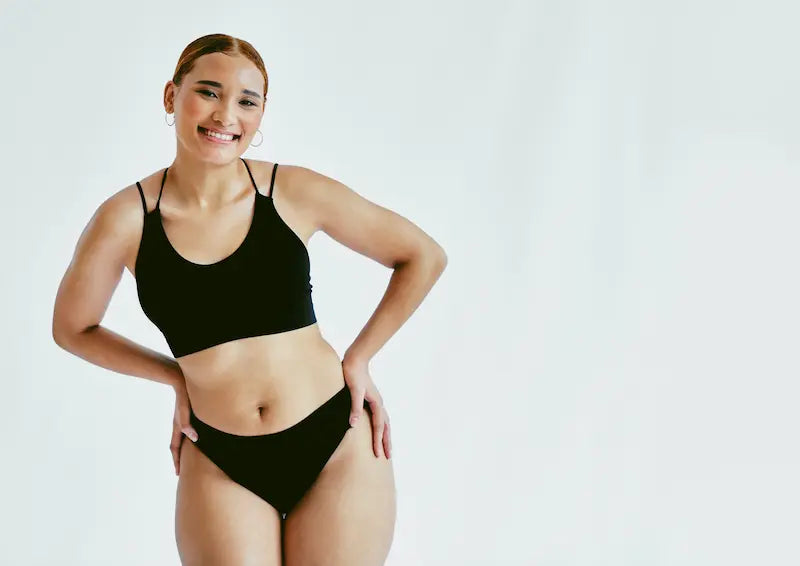 Femme souriante en lingerie noire pour illustrer la santé intime