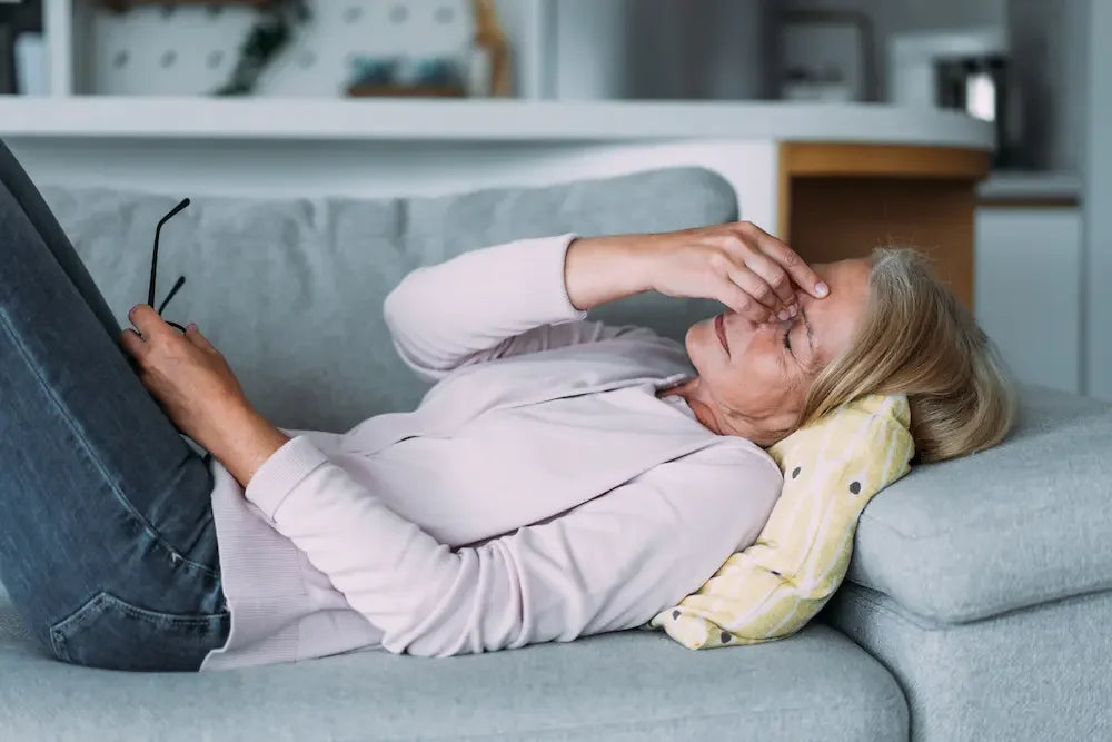 Une femme fatiguée à cause de la ménopause allongée sur un canapé 