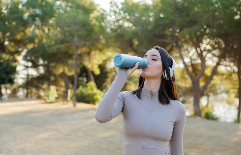 Femme qui boit de l'eau pour éviter courbatures