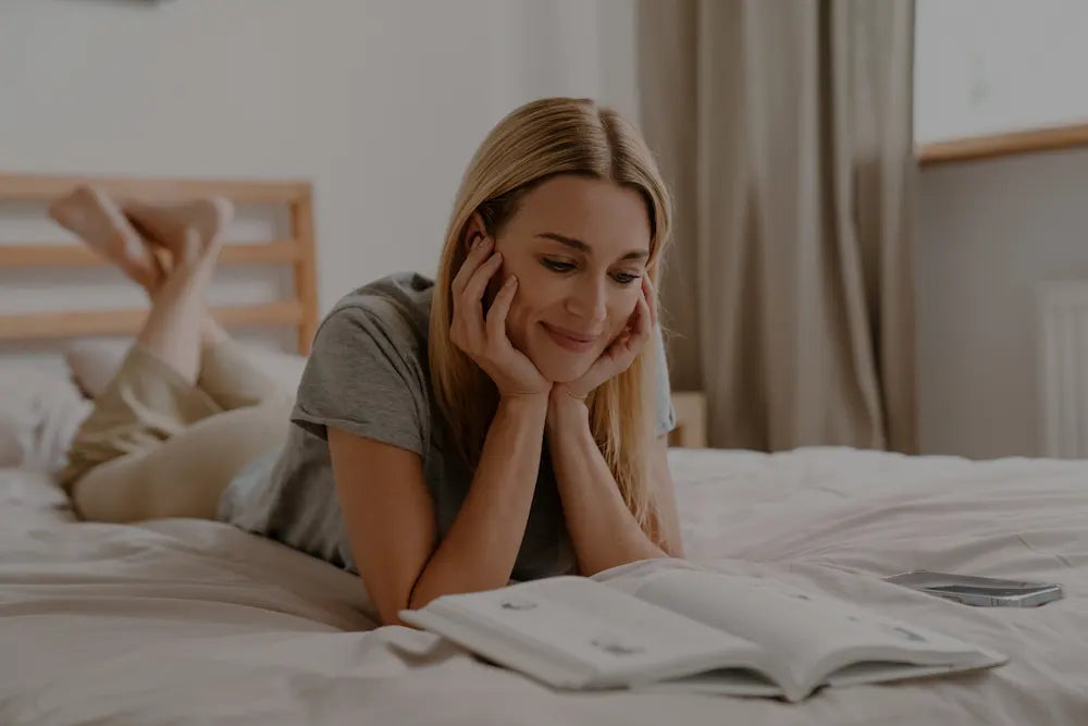 Femme détendue lisant un livre allongée sur son lit